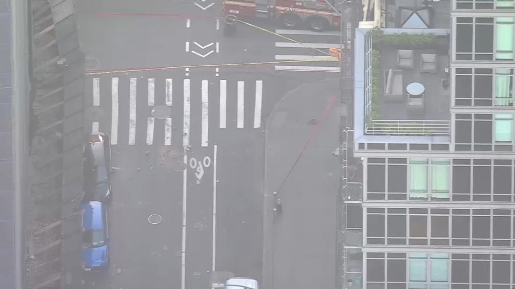 Debris falls from building onto street below in Lower Manhattan, vehicle damaged